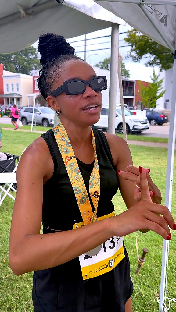 VUU adjunct professor Jasmine Turner, wearing a finisher medal, talks with the VUU desk at the finish festival