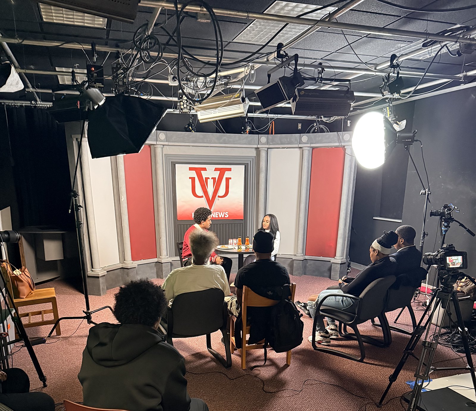 Wide view of the VUU studio during taping, with student audience members, lights and cameras surrounding the interview set.
